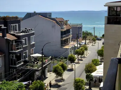 a view of a street with buildings and the ocean at Gnezdo Apartment Sarafovo in Burgas City
