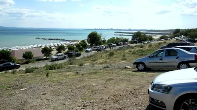 a line of cars parked on a road next to the beach at Gnezdo Apartment Sarafovo in Burgas City