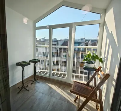 a balcony with a chair and a large window at Уютная квартира рядом с центром Бургаса in Burgas City