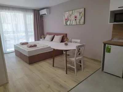a bedroom with a bed and a table and a kitchen at BoriSun with Free Parking space in Burgas City