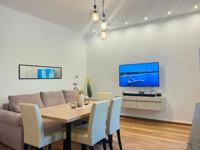 a living room with a table and a tv at Detelina Apartment Bee Happy in Burgas in Burgas City