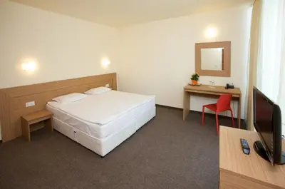 a bedroom with a bed and a desk and a television at Jeravi Club Hotel - All Inclusive in Primorsko