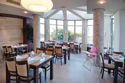 a dining room with tables and chairs and windows at Jeravi Club Hotel - All Inclusive in Primorsko