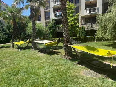 three hammocks in a park with palm trees and a building at Flat in Cascadas 21 in Sunny Beach