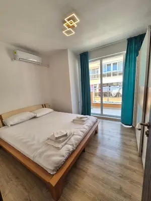 a bedroom with a bed and a large window at Комфортен Апартамент Лазур in Pomorie