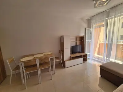 a living room with a dining room table and a tv at Комфортен Апартамент Лазур in Pomorie