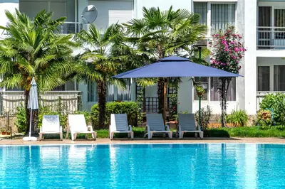 a pool with chairs and an umbrella and palm trees at Apartment E 12 Yassen HV in Sunny Beach
