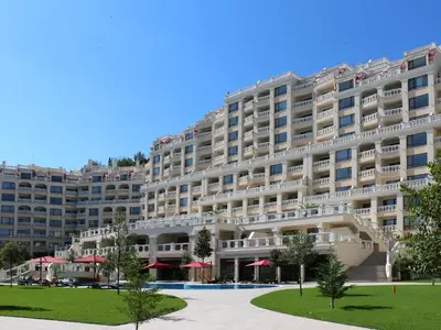 a large building with red umbrellas in front of it at АТ apartment - South Bay Beach Residence in Varna City