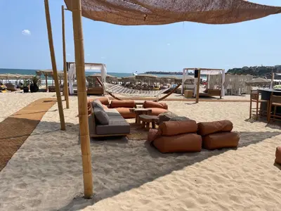 a beach with chairs and an umbrella on the sand at Beachfront Apartment Oasis VIP Club in Sunny Beach