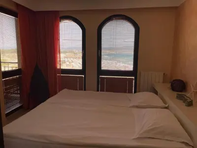 a bedroom with two windows and a bed with white sheets at Beachfront Apartment Oasis VIP Club in Sunny Beach