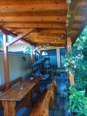 a porch with a wooden bench and a wooden roof at Family Hotel California in Primorsko