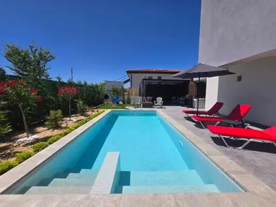 a swimming pool with red chairs and an umbrella at villa Amethyst, private pool with heating and salt water in Lozenets