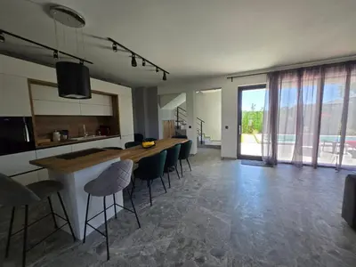 a kitchen and living room with a table and chairs at villa Amethyst, private pool with heating and salt water in Lozenets