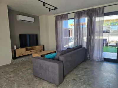 a living room with a couch and a television at villa Amethyst, private pool with heating and salt water in Lozenets