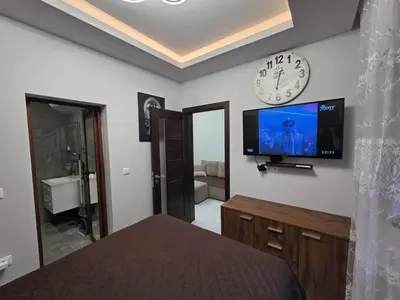 a bedroom with a clock and a television on the wall at DN Kiten in Kiten