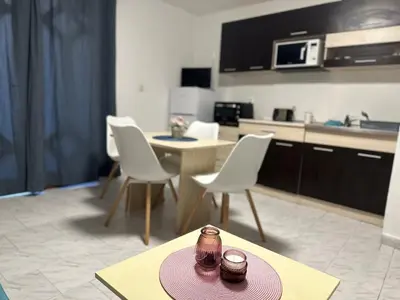 a living room with a table and chairs and a kitchen at Villa Nikoleta in Sveti Vlas
