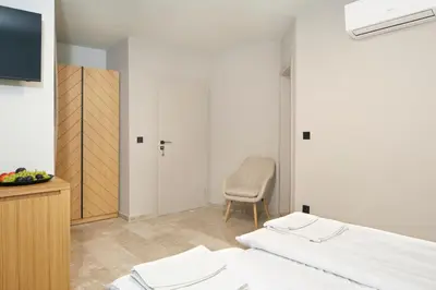 a bedroom with a bed and a chair and a tv at Семеен хотел НОА in Nesebar