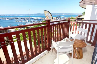 a balcony with two chairs and a table with a view of a harbor at Семеен хотел НОА in Nesebar