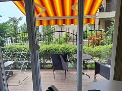 a sliding glass door with a patio with chairs and tables at Delfin beach studio in Sozopol