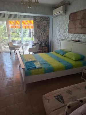 a bedroom with a bed and a desk and windows at Delfin beach studio in Sozopol