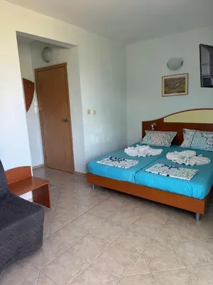 a bedroom with a bed with blue sheets and a couch at Хотел Грация in Lozenets
