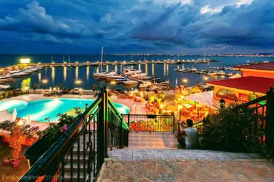 a man sitting next to a pool at a marina at Romantic Studio Florence in Sveti Vlas