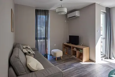 a living room with a gray couch and a television at Green Corner Apartment in the Center - 2BD in Burgas City