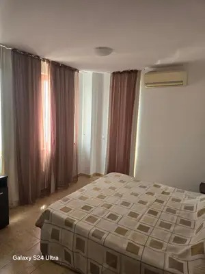 a bedroom with a bed in a room with curtains at Апартамент Хелиос Поморие in Pomorie