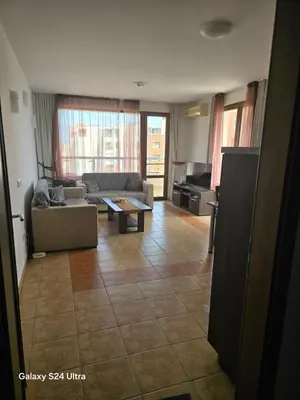 a living room with a couch and a table at Апартамент Хелиос Поморие in Pomorie