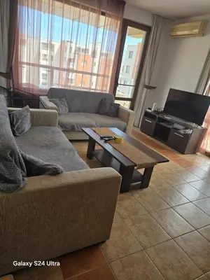 a living room with a couch and a coffee table at Апартамент Хелиос Поморие in Pomorie