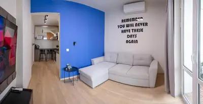 a living room with a white couch and a blue wall at City Center Gem Varna - 5 Guests in Varna City