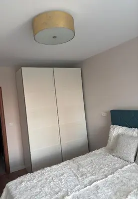 a bedroom with a white bed and a white cabinet at Дизайнерски апартамент in Burgas City