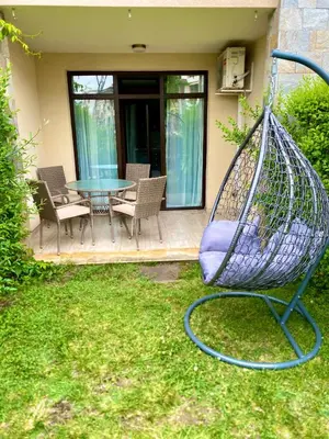 a swing in a yard with a table and chairs at Green life private garden studio in Sozopol