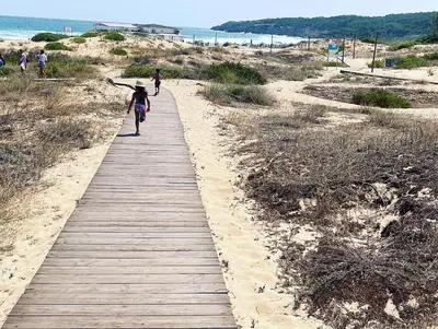 a person riding a bike down a wooden path on the beach at Green life private garden studio in Sozopol