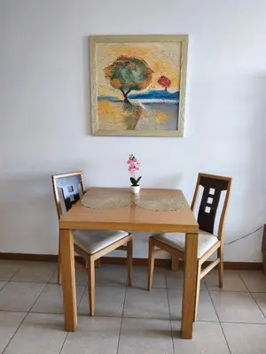 a wooden table with two chairs and a painting on the wall at Emerald Apartman Wellness & Spa in Ravda