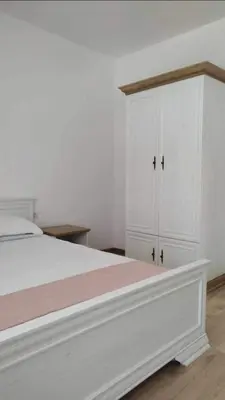 a white bedroom with a white bed and a cabinet at Relax in Tsarevo