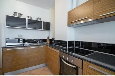 a kitchen with black counter tops and wooden cabinets at The white flat in Byala