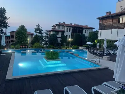 a large swimming pool with chairs next to a building at Cozy Ground-Floor Apartment with Terrace in Sozopol