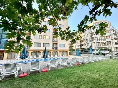 a row of chairs with umbrellas in front of a building at Sunny Sea - Menada Apartments in Sunny Beach