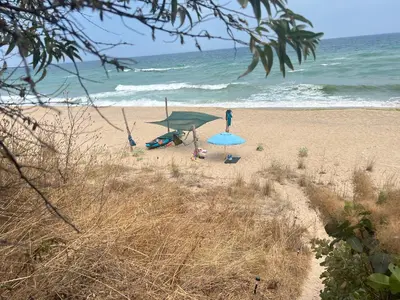 a person standing on a beach with an umbrella at Палатка на Кара Дере in Byala