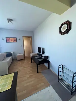 a living room with a table and a clock on the wall at 2-bedroom Apartment in Marina Holiday Club Pomorie in Pomorie