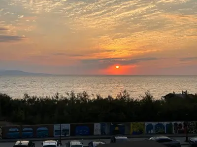 a sunset over the water with cars in a parking lot at Sunrise Apartment in Pomorie