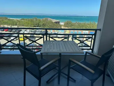 a table and chairs on a balcony with the beach at Sunrise Apartment in Pomorie