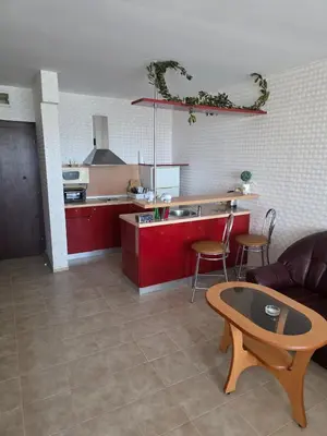 a kitchen with red cabinets and a table and a couch at Apartment Miramar Palace in Sunny Beach