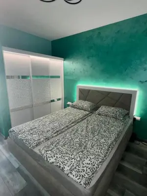 a bedroom with a bed with a green wall at Апартамент Велкови in Tsarevo