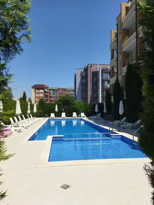 a swimming pool with chairs and a building at Святая Елена in Sunny Beach