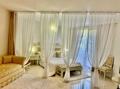 a bedroom with a bed with curtains and a couch at Luxury Coastal Dreams Apartment in Sveti Vlas