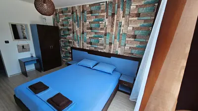 a bedroom with a blue bed and a brick wall at Apartment 16 - Rainbow Holiday Complex in Sunny Beach