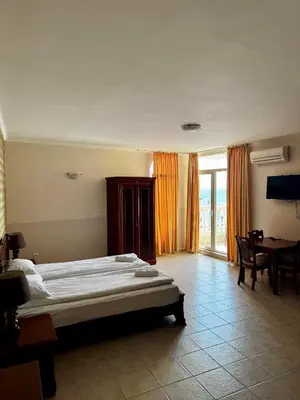 a bedroom with a bed and a table and a window at Sea View Apartment Sveti Vlas in Sveti Vlas