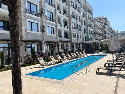 a pool with chairs and umbrellas next to a building at Onyx Sveti Vlas частни апартаменти in Sveti Vlas